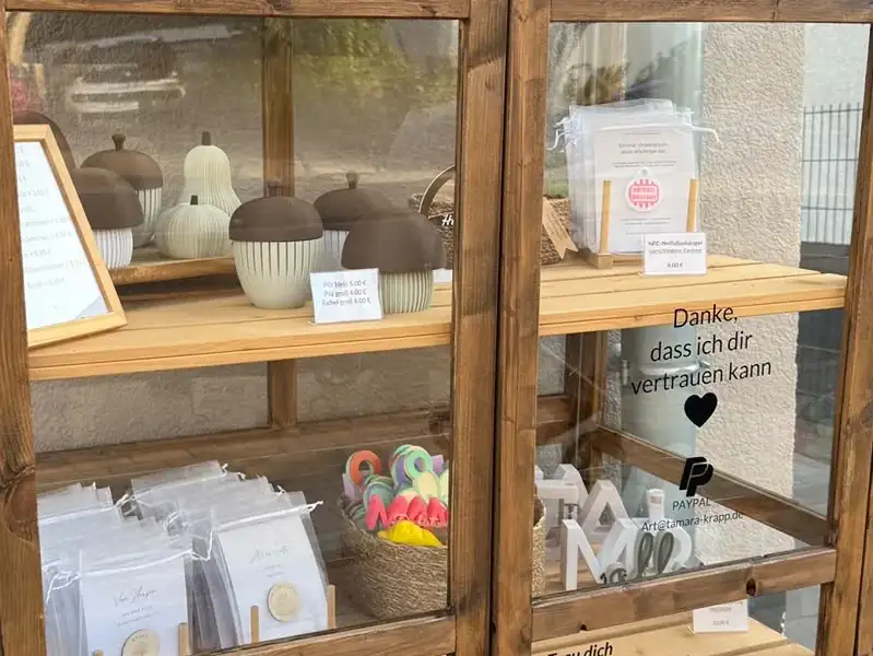 Blick durch die Glastür des Kreativschranks: Pilze und Eicheln aus dem 3D-Drucker, NFC-Notfallanhänger, Karten und der Hinweis zum Bezahlen per PayPal